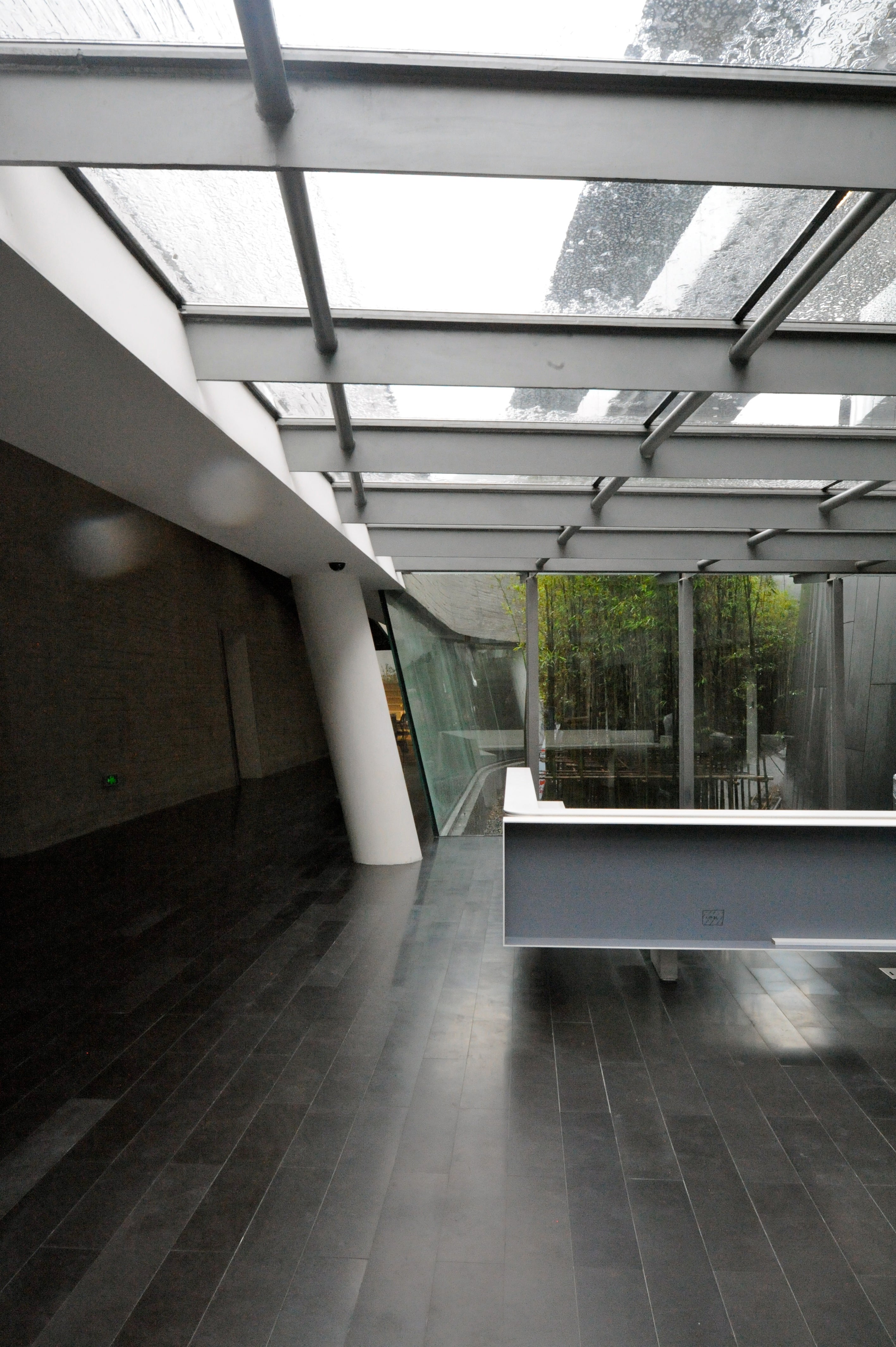 Office entry breaks down barriers between inside and outside with glass ceiling and bamboo-filled courtyard.