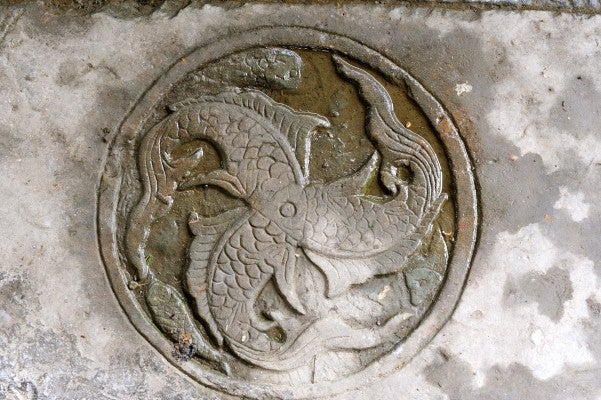 Emblem in paving that depicts the cooperation of three cultures--three fishes with one head.
